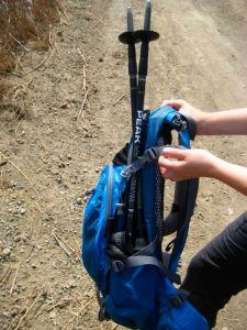 Trekking pole storage in a backpack that has side pockets and built in cinch straps